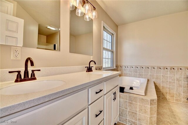 bathroom with double vanity, tile patterned flooring, a sink, and a bath