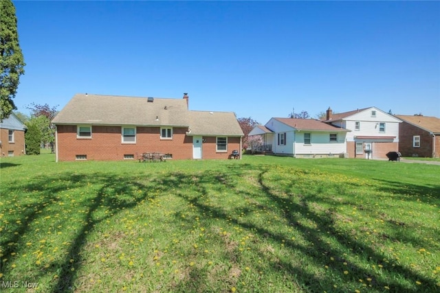 rear view of house with a lawn and a chimney