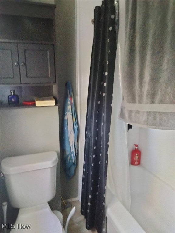 bathroom with a shower with shower curtain and toilet