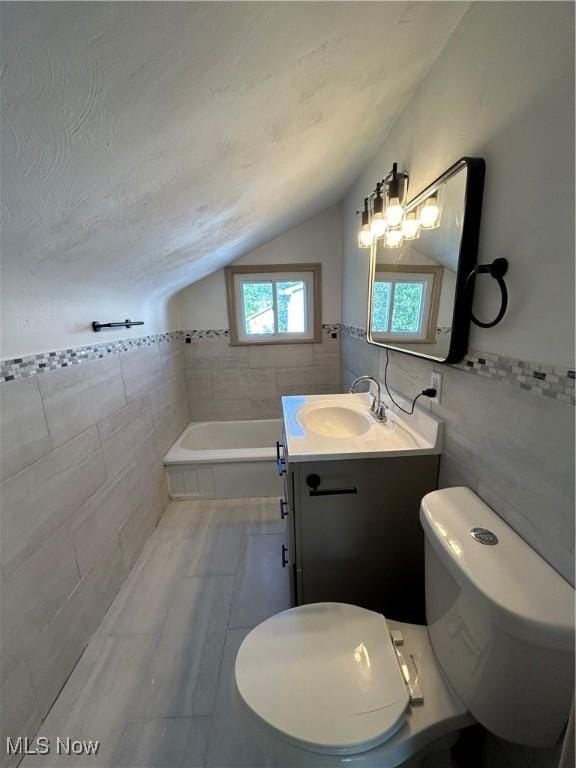 bathroom featuring toilet, tile walls, a bathtub, and lofted ceiling