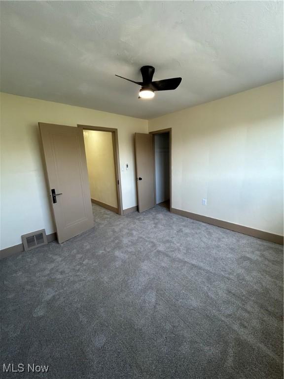 unfurnished bedroom featuring visible vents, a closet, baseboards, ceiling fan, and carpet