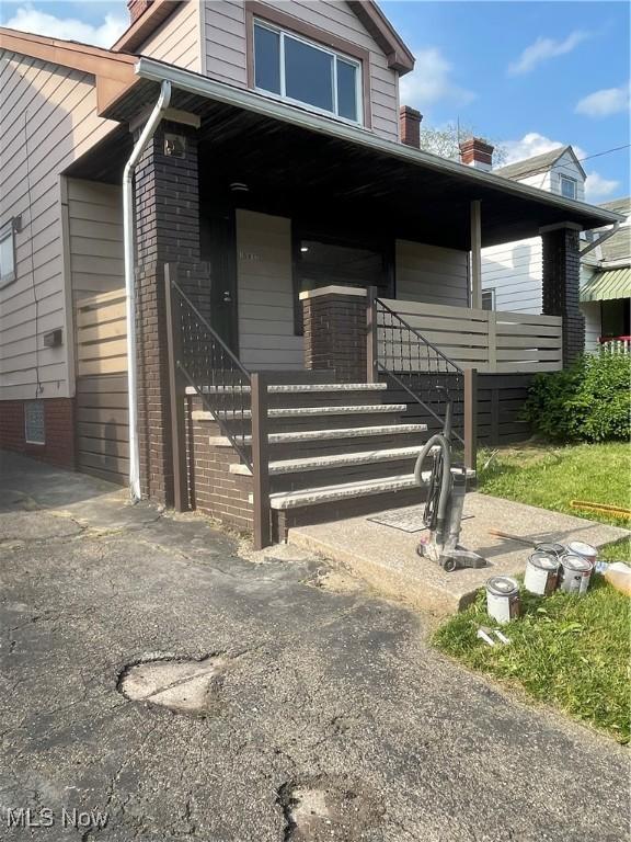 view of front of house with a porch, a chimney, and brick siding