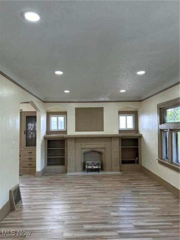 unfurnished living room with baseboards, recessed lighting, wood finished floors, and a fireplace