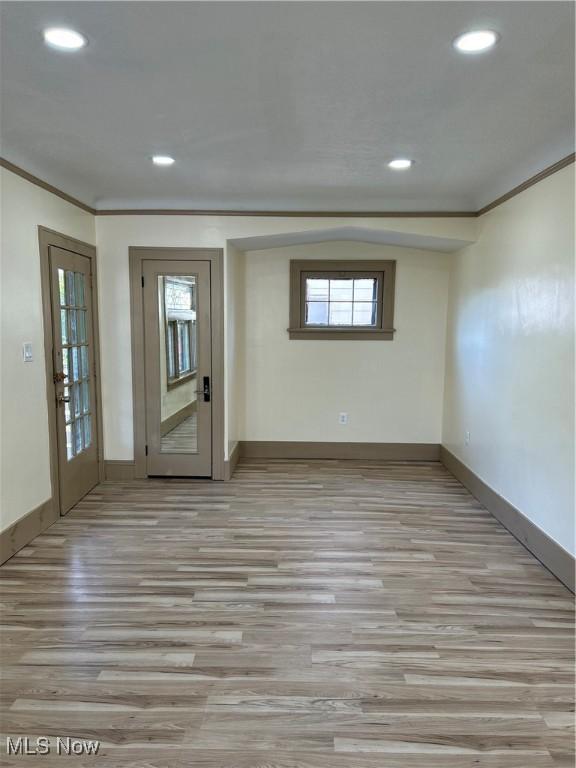 spare room featuring crown molding, baseboards, recessed lighting, and light wood-style flooring