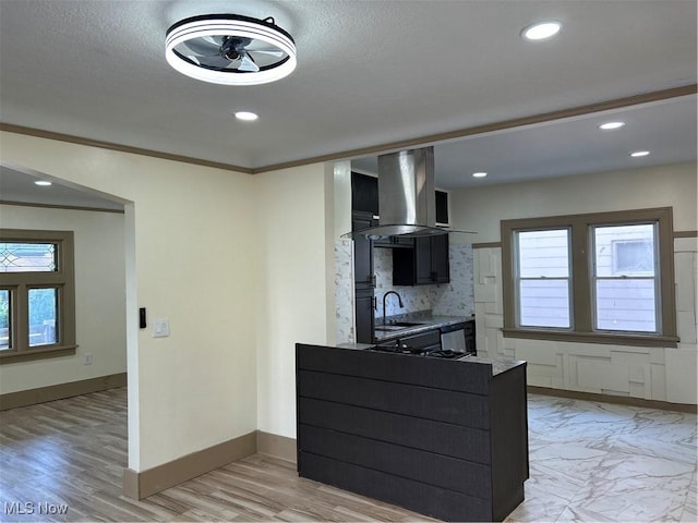 kitchen with decorative backsplash, plenty of natural light, island range hood, a sink, and baseboards