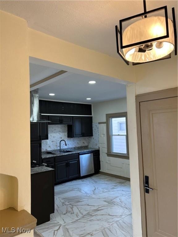 kitchen with marble finish floor, tasteful backsplash, dark cabinets, a sink, and dishwasher