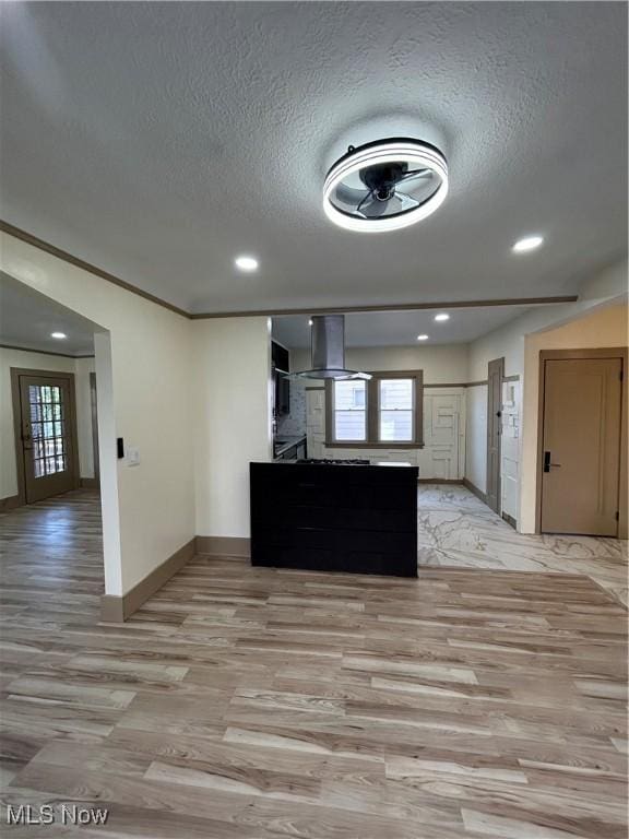 kitchen featuring a textured ceiling, wall chimney exhaust hood, baseboards, recessed lighting, and light wood-style flooring
