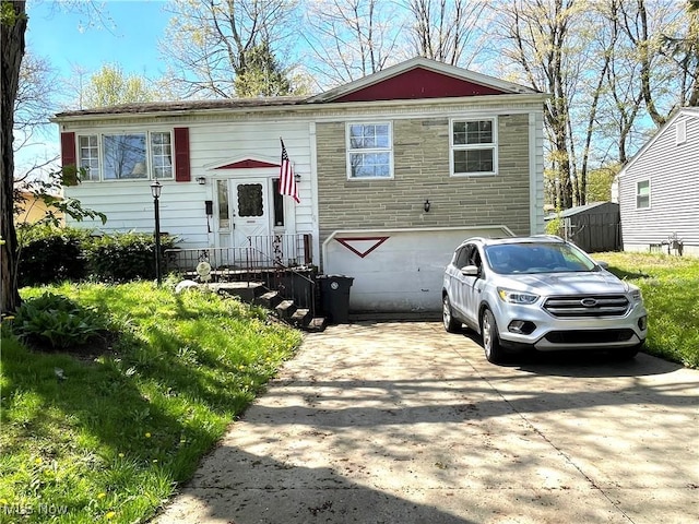 split foyer home with stone siding and concrete driveway