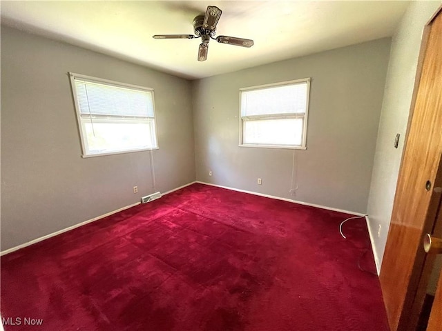 empty room featuring visible vents, carpet flooring, a ceiling fan, and a healthy amount of sunlight