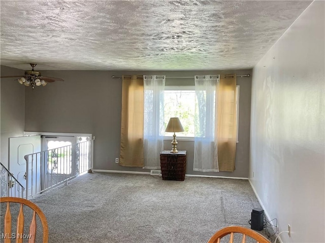 living area featuring a textured ceiling, baseboards, and carpet