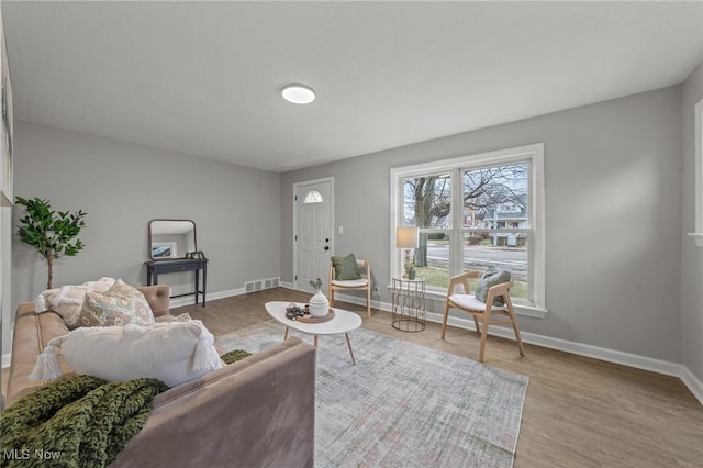 living area featuring baseboards, visible vents, and wood finished floors