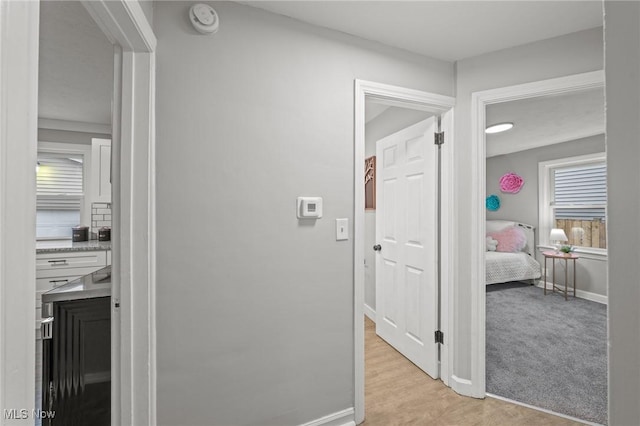 hall with baseboards and light wood-style floors