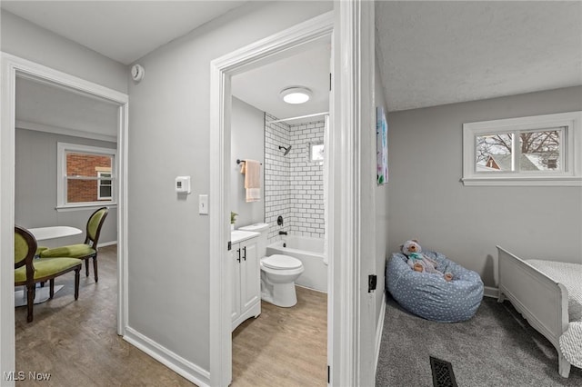bathroom featuring baseboards, bathing tub / shower combination, a wealth of natural light, and vanity