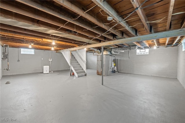 below grade area with stairway, heating unit, and water heater