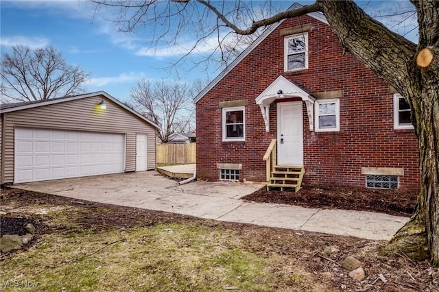 view of front of property with fence, brick siding, a garage, entry steps, and an outbuilding