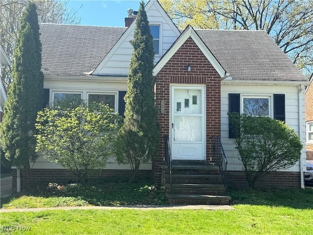 view of front of property with a chimney, entry steps, and a front lawn