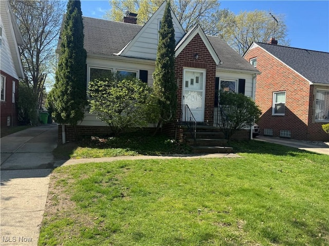 bungalow-style home with brick siding, a front lawn, and a chimney