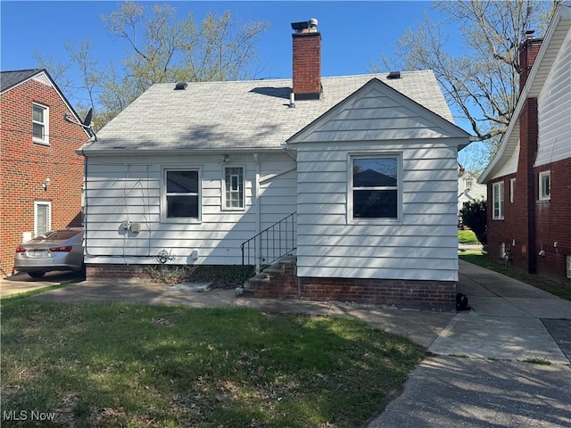 back of property with a chimney and a shingled roof