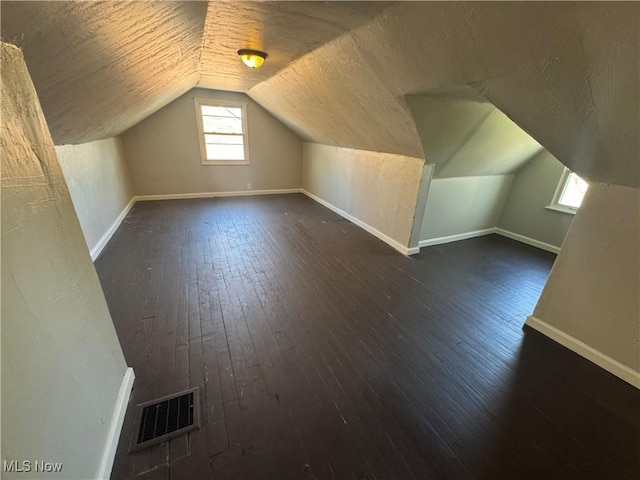 bonus room featuring baseboards, lofted ceiling, hardwood / wood-style floors, and visible vents