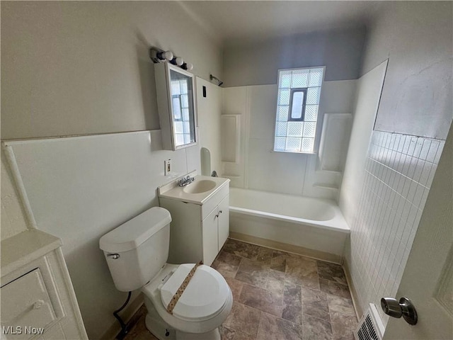 bathroom with toilet, stone finish flooring, tub / shower combination, and plenty of natural light