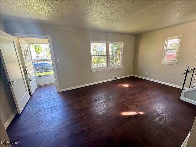 unfurnished living room featuring plenty of natural light, dark wood-style floors, and a textured ceiling