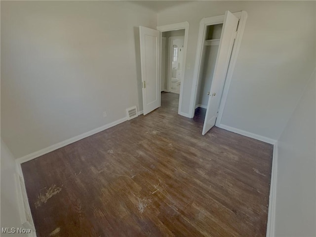 unfurnished bedroom featuring baseboards, wood finished floors, visible vents, and a closet