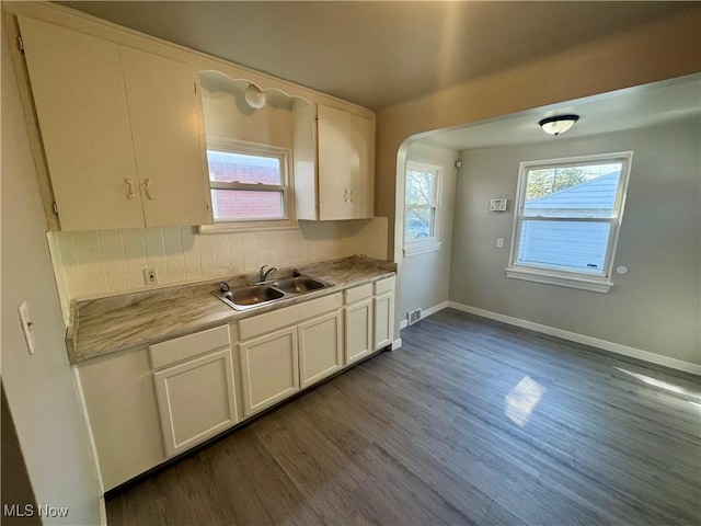 kitchen featuring a sink, light countertops, baseboards, decorative backsplash, and dark wood-style floors