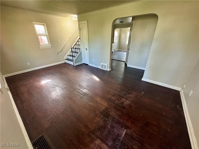 interior space with visible vents, baseboards, stairway, dark wood-type flooring, and arched walkways