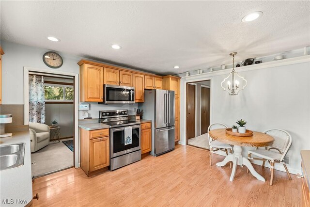 kitchen featuring light wood-style floors, stainless steel appliances, recessed lighting, and a chandelier
