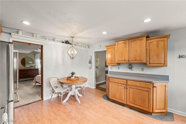 kitchen with pendant lighting, baseboards, freestanding refrigerator, and light wood-type flooring