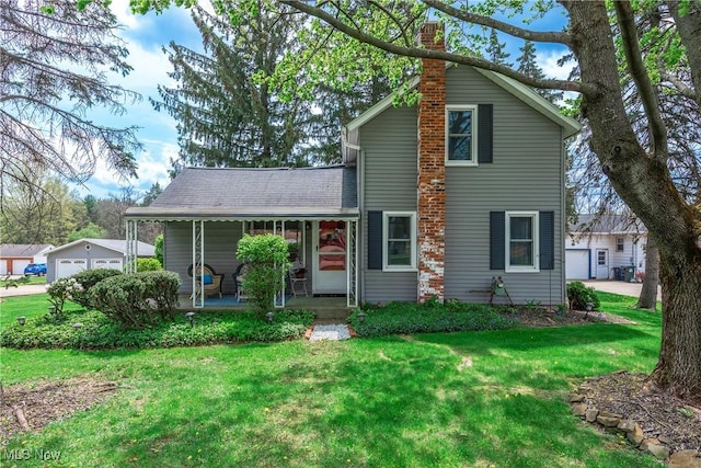 traditional-style house featuring a garage, a front lawn, covered porch, and a chimney