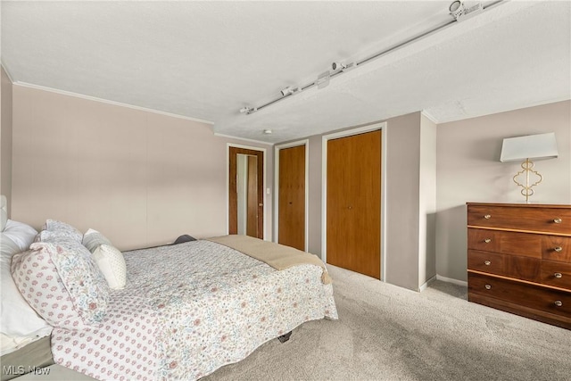bedroom with multiple closets, ornamental molding, carpet, and baseboards