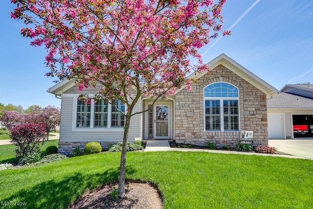 ranch-style home featuring an attached garage, a front lawn, driveway, and stone siding