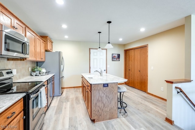 kitchen with a sink, baseboards, stainless steel appliances, and light wood-type flooring