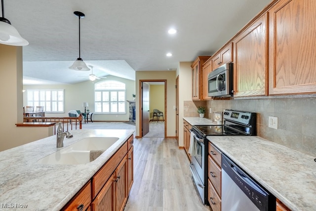 kitchen featuring decorative backsplash, light countertops, a sink, hanging light fixtures, and stainless steel appliances