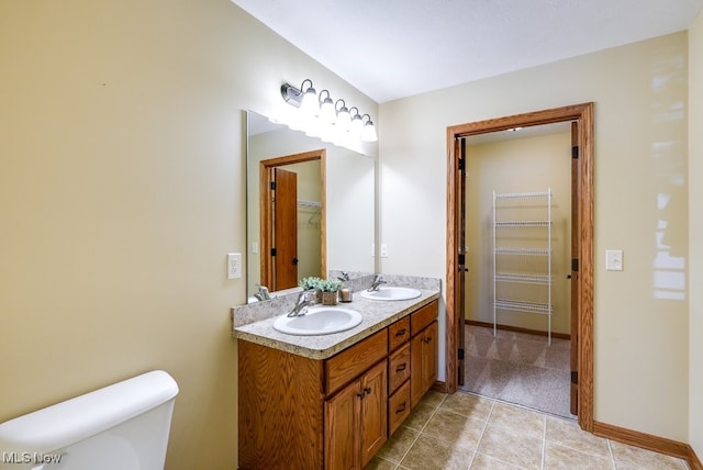 bathroom featuring a sink, tile patterned floors, baseboards, and toilet
