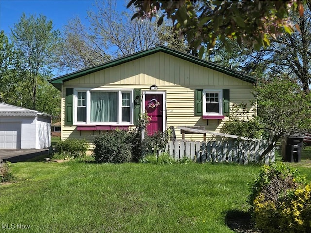 bungalow-style house featuring a detached garage, an outbuilding, and a front lawn