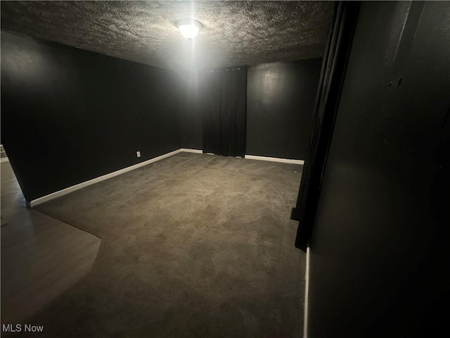 carpeted spare room featuring baseboards and a textured ceiling