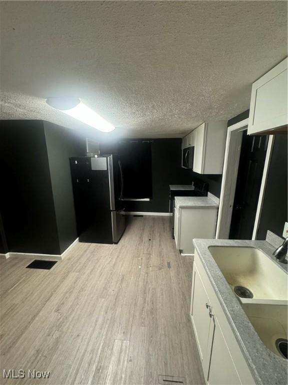 kitchen featuring freestanding refrigerator, a textured ceiling, and range