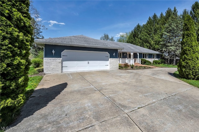 single story home featuring a porch, an attached garage, driveway, and stone siding