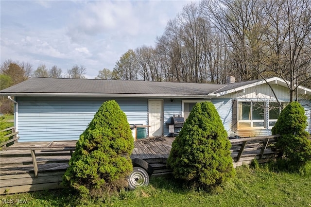 view of side of home featuring a shingled roof, a wooden deck, and a chimney