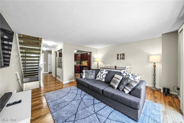 living area with baseboards, stairs, wood finished floors, and visible vents