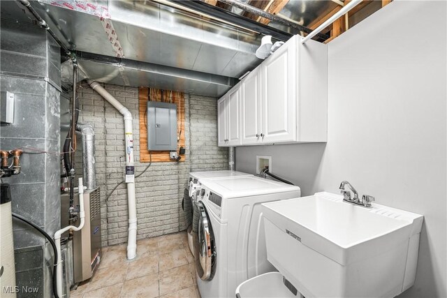 laundry area with brick wall, electric panel, separate washer and dryer, a sink, and cabinet space