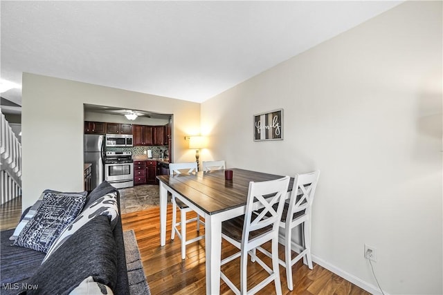 dining area featuring stairway, baseboards, a ceiling fan, and light wood-type flooring