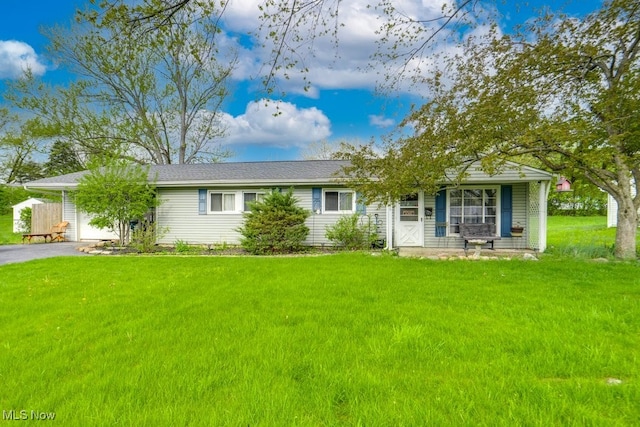 ranch-style home featuring covered porch, an attached garage, aphalt driveway, and a front yard