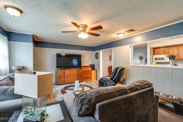 carpeted living area with a ceiling fan, a textured ceiling, visible vents, and ornamental molding