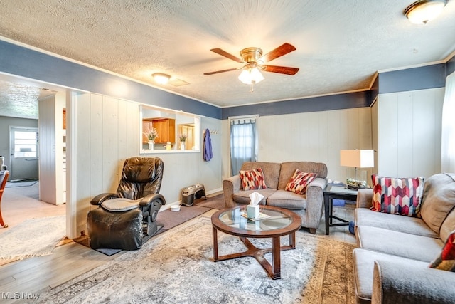 living room with crown molding, a textured ceiling, ceiling fan, and wood finished floors