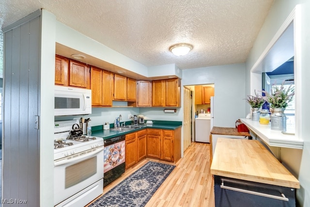 kitchen with a sink, light wood-style floors, white appliances, a textured ceiling, and washer / clothes dryer