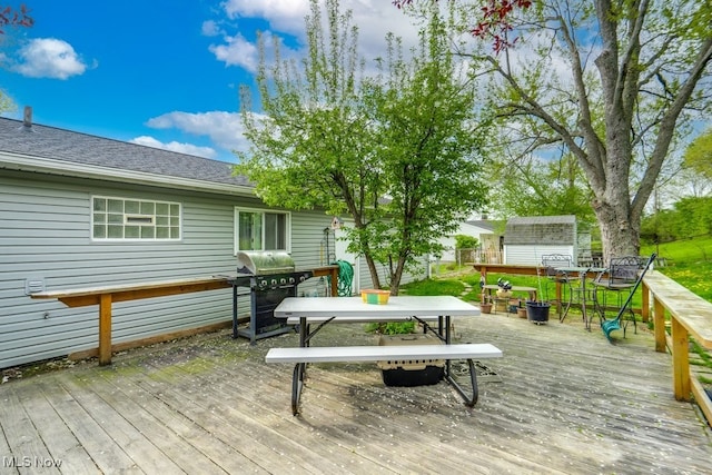 deck with grilling area, an outbuilding, outdoor dining space, and a storage unit