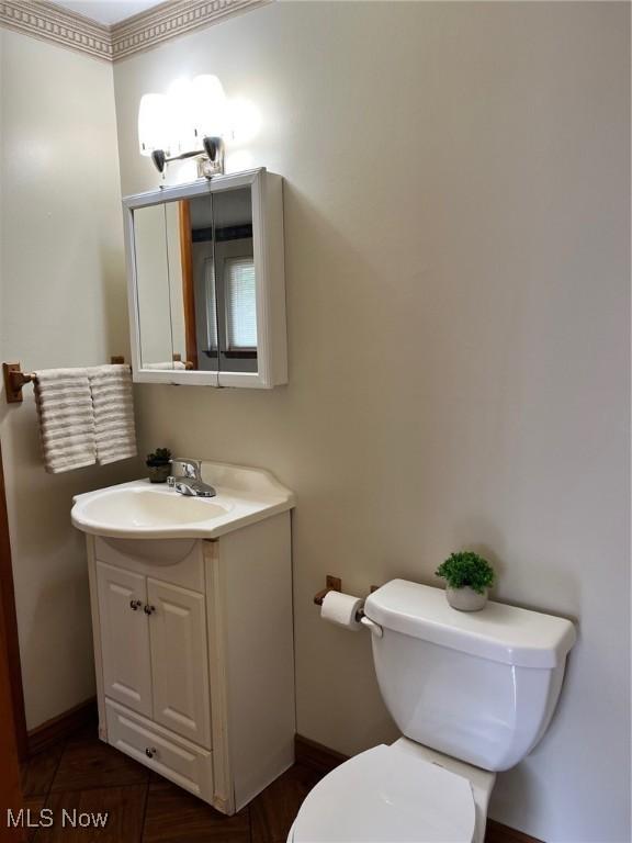bathroom with toilet, baseboards, and vanity